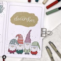 an open notebook with christmas gnomes and the words december written on it, surrounded by crayons