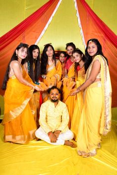 a group of people standing next to each other in front of a red and yellow tent