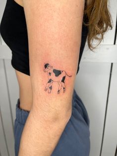 a woman's arm with a small cow tattoo on it