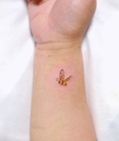 a small tattoo on the wrist of a woman's arm, with a yellow butterfly