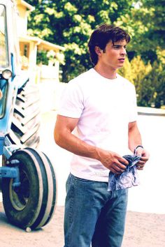 a man standing in front of a tractor with his hands in his pockets and looking off to the side