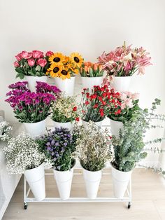 a bunch of flowers that are in some white pots on a table and one is yellow