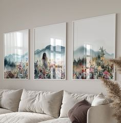 three paintings hang on the wall above a couch in a living room with white furniture