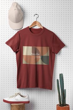 a t - shirt hanging up on a wall next to a hat and cactus plant