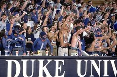 a group of people that are standing in front of a sign with the words duke university on it