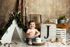 a baby sitting on the floor next to a cake