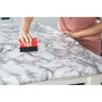 a person with their hand on a block of black and white marbled paper that is placed on top of a table