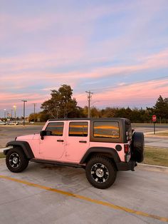 a pink jeep is parked in a parking lot