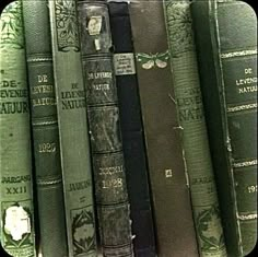 an assortment of old books are stacked on top of each other in a row,