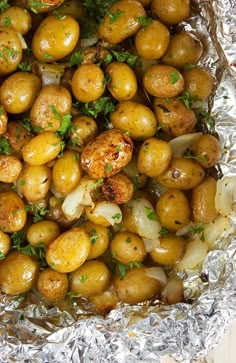 cooked potatoes and onions in foil with parsley garnish on top, ready to be eaten