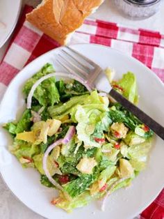 a white plate topped with salad next to bread