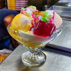 three scoops of ice cream in a glass bowl on a table with other food items