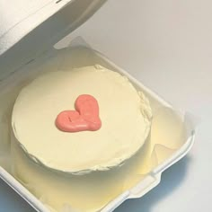 a cake in a box with a heart on it's top and frosting