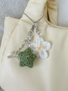 a crocheted flower is attached to a chain on a white fabric bag,