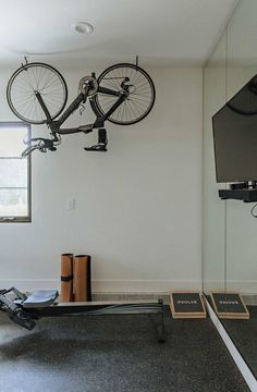 a bike hanging from the ceiling in a living room with two books and a tv