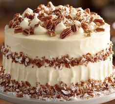 a cake with white frosting and pecans on top