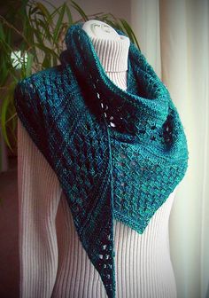 a green knitted shawl hanging on a mannequin