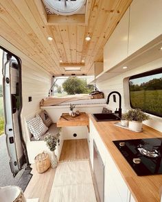 the interior of a camper with wood flooring and white walls, including a kitchen counter