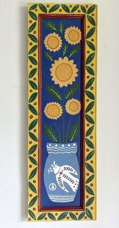 a painting with sunflowers in a blue vase on a white wall next to a green and yellow border