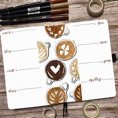 an open notebook with coffee art on it and some scissors next to it, along with other items