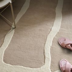 two pairs of pink slippers sitting on top of a white rug next to a chair