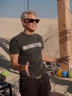 a man standing in front of a wooden pole with balls on it and wearing sunglasses