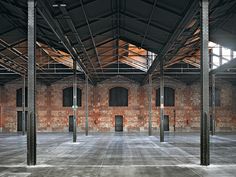 an empty warehouse with exposed brick walls and metal bars on the floor, as well as large windows