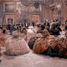 a group of people sitting around each other in fancy dresses and bonnets on the floor