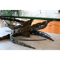 a glass table topped with metal alligators sitting on top of a white tile floor