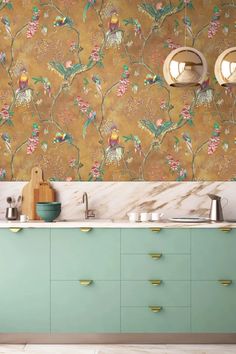 a kitchen with green cabinets and gold wallpaper