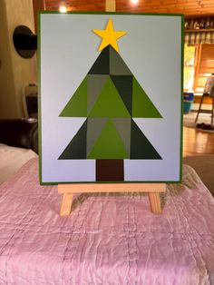 a small wooden christmas tree sitting on top of a pink tablecloth covered bed in a living room