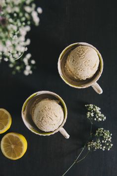 two mugs filled with ice cream next to lemon slices and baby's breath flowers