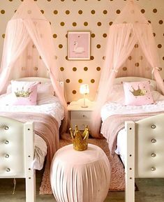 two white beds with pink and gold decor in a girls'bedroom, one has a princess crown on it