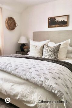 a bed with white sheets and pillows in a bedroom