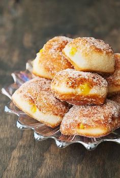 a pile of sugar covered donuts sitting on top of a glass plate