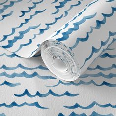 a blue and white wallpaper with watercolor waves on the paper, as well as a roll of tape