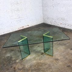 a glass table sitting on top of a floor next to a white brick wall and cement floor