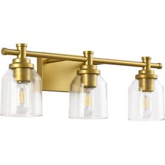 three light bathroom fixture with clear glass shades and gold metal finish on an aged brass wall