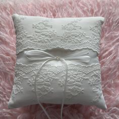 a white pillow with a bow on it sitting on a pink furnishing area