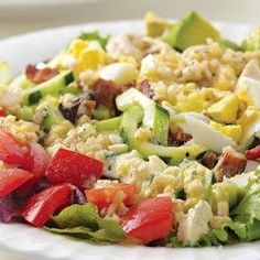 a salad with chicken, lettuce, tomatoes and other vegetables on a white plate