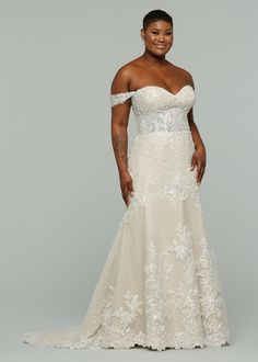 a woman in a wedding dress posing for the camera with her hands on her hips