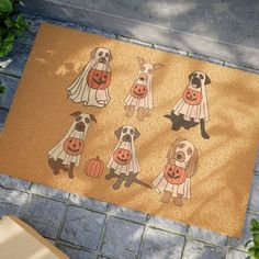 a door mat with four dogs dressed up as ghostes and pumpkins on it