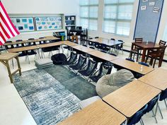 an empty classroom with desks and chairs in front of the american flag on the wall