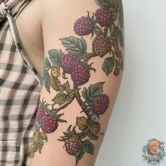 a woman's arm with tattoos on it and raspberries growing on the branch