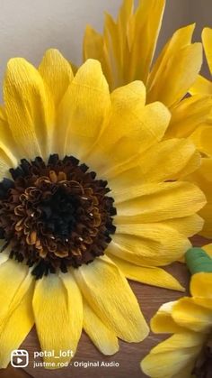 two yellow flowers sitting on top of a wooden table