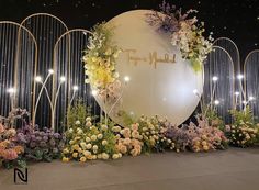 an outdoor display with flowers and lights on the wall, in front of a circular sign that says happy mother