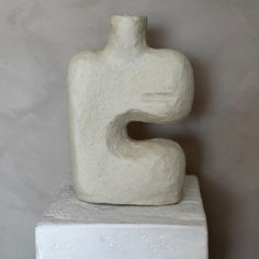 a white sculpture sitting on top of a cement block