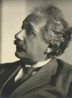 an old black and white photo of a man with curly hair wearing a suit and tie