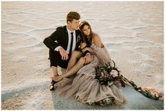 a man and woman are sitting on the ground together, posing for a photo in their wedding attire