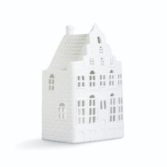 a small white house shaped like a model on a white surface with windows and shutters